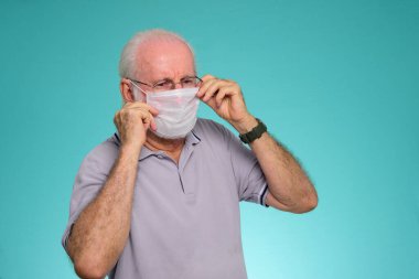 Sağlık hizmetleri için ilaç maskesi kullanan yaşlı Brezilyalı bir adamın portresi, yeşil arka planda Covid-19 ve Hava kirliliği pm2.5 'u koruyor..