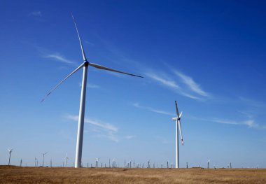 Mavi gökyüzüne karşı bir tarlada rüzgar türbini.