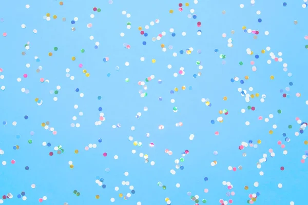 Mavi kağıda saçılmış çok renkli konfeti.