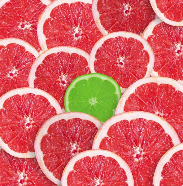 Green slice of lime between red slices of grapefruit.