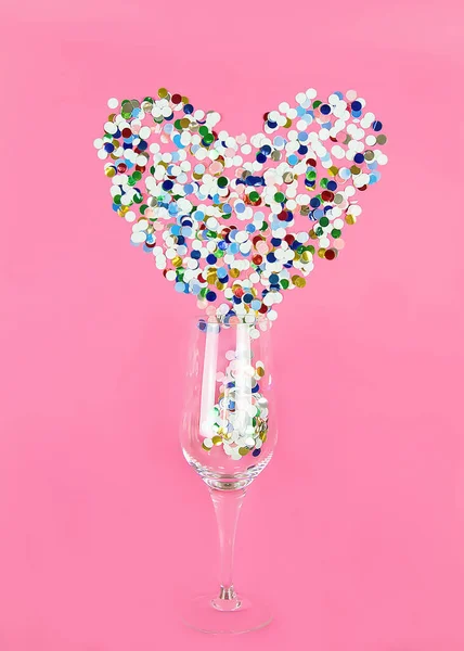 a glass of champagne on a pink background