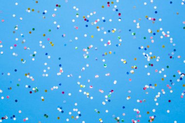 Colored confetti scattered on blue pastel paper