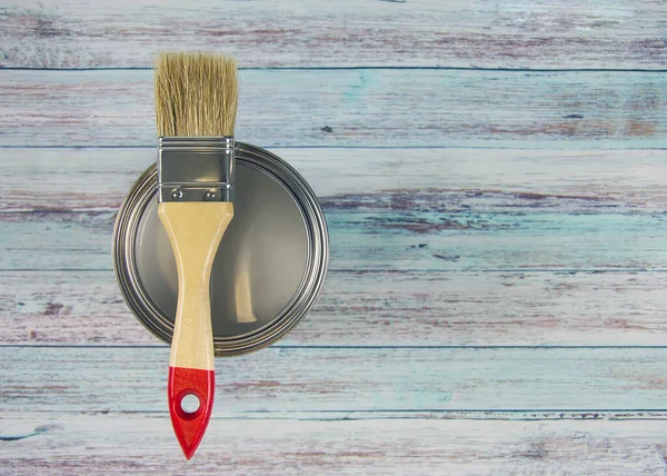 brush and can of paint on wooden background