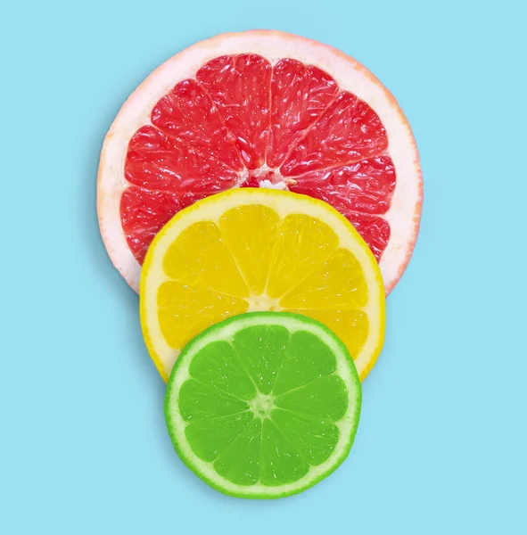 Fresh slices of grapefruit, lemon and lime on a blue background.