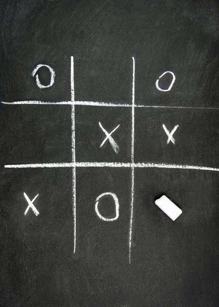 game tic-tac-toe on a chalk board and a piece of chalk
