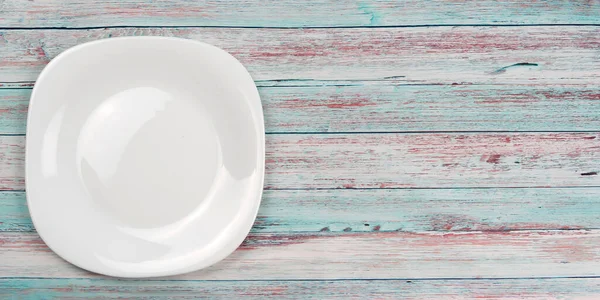 Ahşap zemin üzerinde boş beyaz tabak.