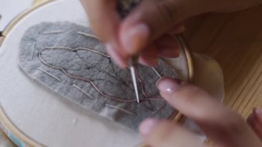 Yakın plan profesyonel mücevher tasarımcısı stüdyo atölyesinde boncuklarla el yapımı broş yapıyor. Moda yaratıcılığı ve el yapımı konsept.