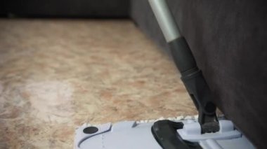 Profesyonel bir temizlikçiyle birlikte temizlik şirketinden bir adam oturma odasında yerleri yıkıyor. 