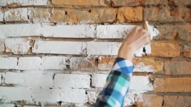 Kızların ellerinde beyaza boyanmış kırmızı tuğla boya fırça onarıyor. 