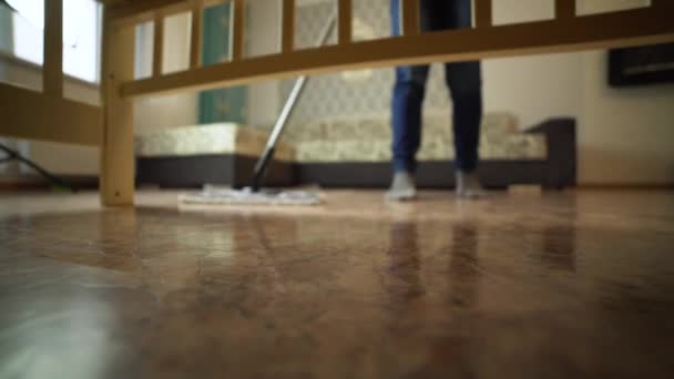 清掃会社の男性がリビングルームで床を洗っています — ストック動画