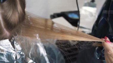Saç kurutma makinesiyle uzun kahverengi saç boyası ve yakın bir tarakla saç boyama.