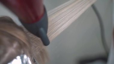 Saç kurutma makinesiyle uzun kahverengi saç boyası ve yakın bir tarakla saç boyama. 