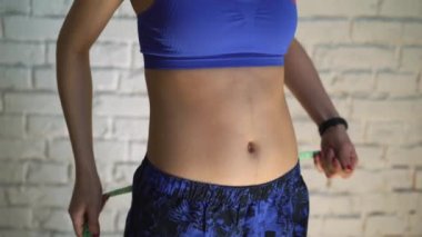 Formda sporcu kadının vücut ölçüsünü spor sonrası kilo verme kavramından sonra bant ile ölçtüğü yakın plan görüntüsü