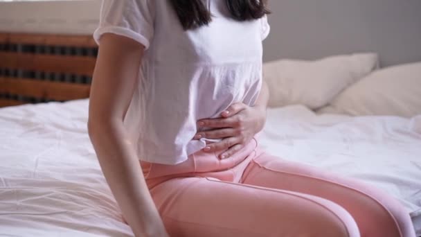 年轻女子坐在床上 肚子痛 — 图库视频影像