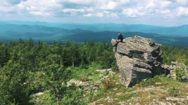 Genç adam ellerini büyük bir dağın tepesine kaldırır.