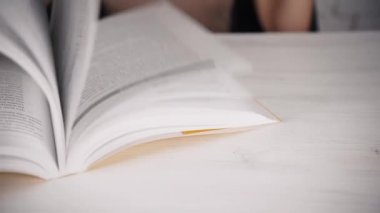 Gözlüklü, beyaz bir masada oturan kız kötü görme gücü olan bir kitap günlüğü okuyor.
