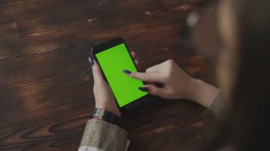 Yeşil ekran yeşil ekranda elinde akıllı telefon tutan güzel bir kız. 