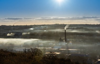 a city on the island of Sakhalin in Russia in the morning in the fog and smoke of factory pipes clipart