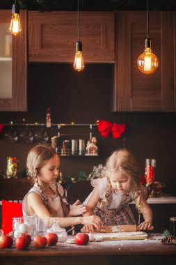 Önlüklü kızlar karanlık bir mutfakta zencefilli ekmek yerler.