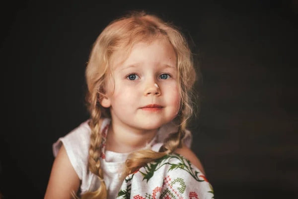 Mooi Klein Meisje Blond Een Donkere Keuken Eten Een Wortel — Stockfoto