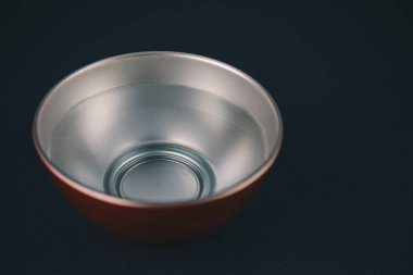 Kırmızı ve gümüş kâse, içinde su var, siyah arka planda izole edilmiş..