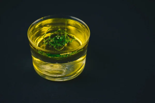 Sapone verde che cade su olio d'oliva in un bicchiere basso . — Foto Stock