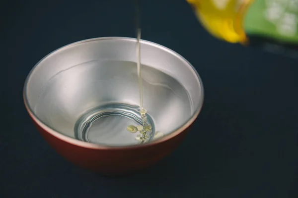 Huile d'olive tombant sur l'eau dans un bol rouge et argent avec bouteille d'huile de référence — Photo