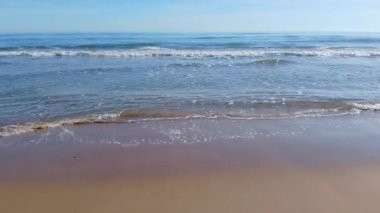 ENTERING THE SEA FROM THE SAND ON A SUNNY DAY WITH A BLUE SKY. 