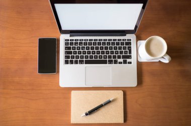Ofis masası, defter, akıllı telefon, dizüstü bilgisayar ve beyaz kahve fincanı. Yukarıdan bak. İş, iletişim ve teknoloji kavramı