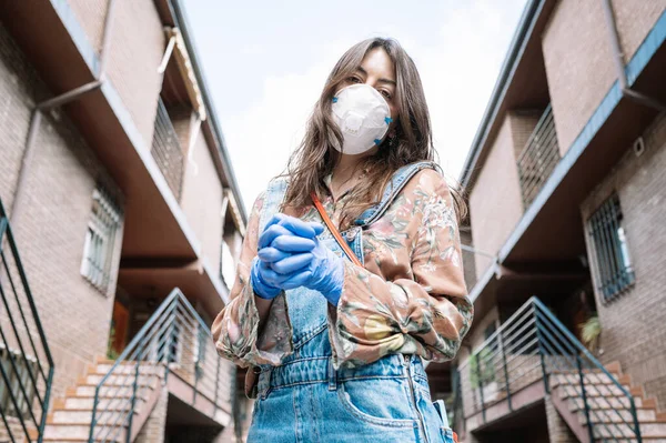 Protection against Covid-19. Young Caucasian woman wearing a mask and medical gloves interlacing her fingers as a sign of unity in difficult times. Concept of unity and protection against the virus.