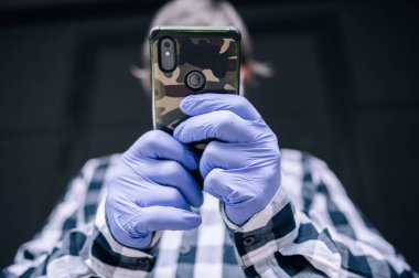 Tıbbi eldivenlerle akıllı bir telefonu tutmak. Mekanı kopyalamak. Koruma ve teknoloji kavramı.