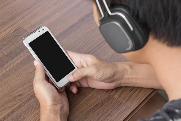 Man hand holding smartphone on wooden table — Stock Photo, Image