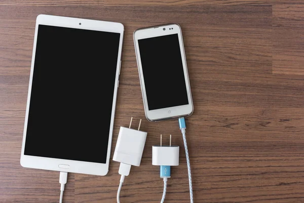 Кабели зарядного устройства соединяются со смартфоном и планшетом — стоковое фото
