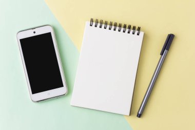 Not defteri smartphone ve kalemi pastel arka plan üzerinde