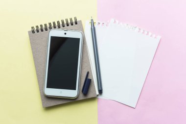 Not defteri smartphone ve kalemi pastel arka plan üzerinde
