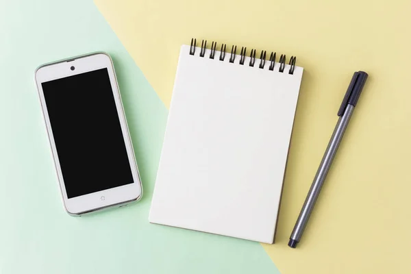 Smartphone notebook e penna su sfondo pastello — Foto Stock