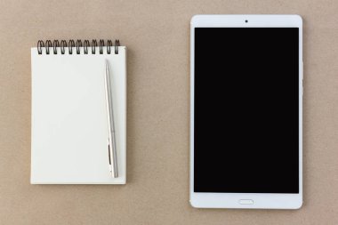 dizüstü ve tablet üzerinde kahverengi arka planda Üstten Görünüm