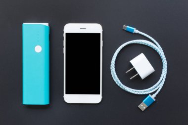Beyaz smartphone ile pil banka ve şarj kablosu siyah bac üzerinde
