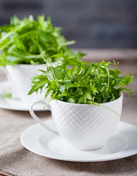 Rugula verde fresco in tazza bianca sul tavolo di legno — Foto Stock