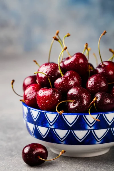 Black cherries in a bowl. Grey stone background.