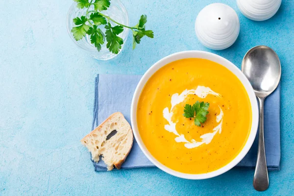 Pumpkin and carrot soup with cream and parsley on blue stone background. Top view. Copy space — Stock Image Pumpkin and carrot soup with cream and parsley on blue stone background. Top view. Copy space Royalty Free Stock Photos