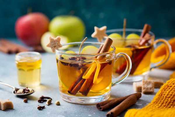 Apple mulled cider with spices in glass cup. Grey stone background. Close up.