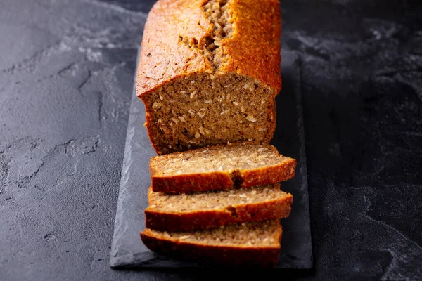 Banana, coconut bread, cake on slate board. Dark stone background.