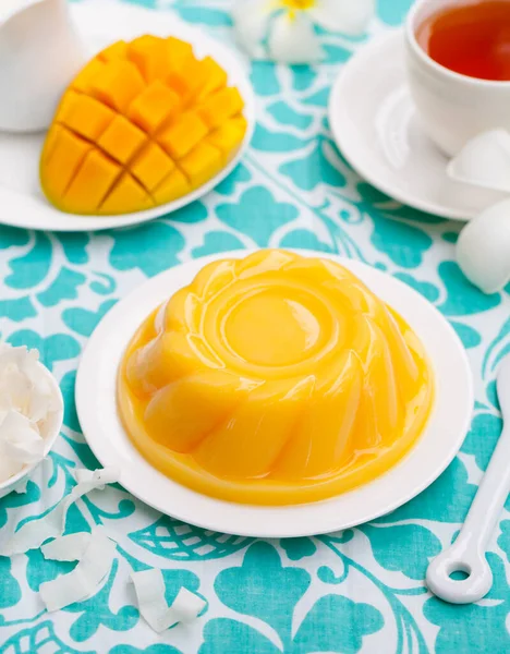 Mango pudding, jelly on white plate with cup of tea. Colorful background.