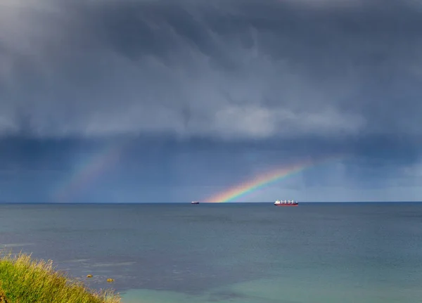 Double rainbow out at sea over a few boats
