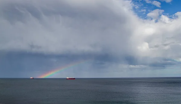Double rainbow out at sea over a few boats