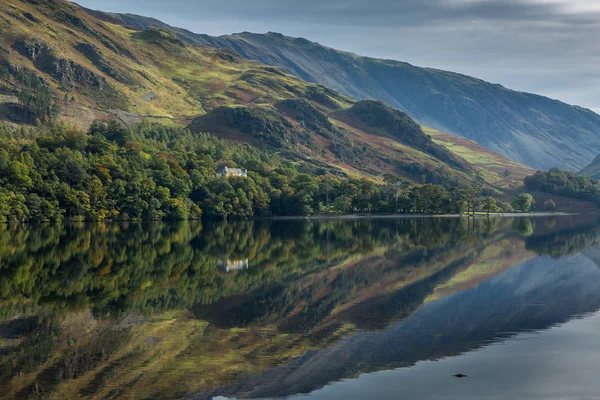 A perfectly still Lake Buttermere on a breathless day in the Lake District, reflecting the beautiful autumn colours which are starting to show in the trees.