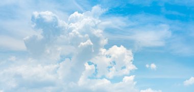 Bulutlar ve güneş ışığıyla yumuşak mavi bir arkaplan.