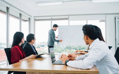 İş adamı bir toplantıda meslektaşlarına sunum yapıyor. Takım lideri ve iş sahibi, resmi olmayan bir iş toplantısına liderlik ediyor. Önplanda dizüstü bilgisayarda çalışan iş adamı.
