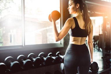 Spor salonunda spor yapmak için haltercilik oynayan genç bir kız, spor salonunda ağır halterleri kaldırıyor. Spor konsepti yağ yakma ve sağlıklı bir yaşam tarzı.